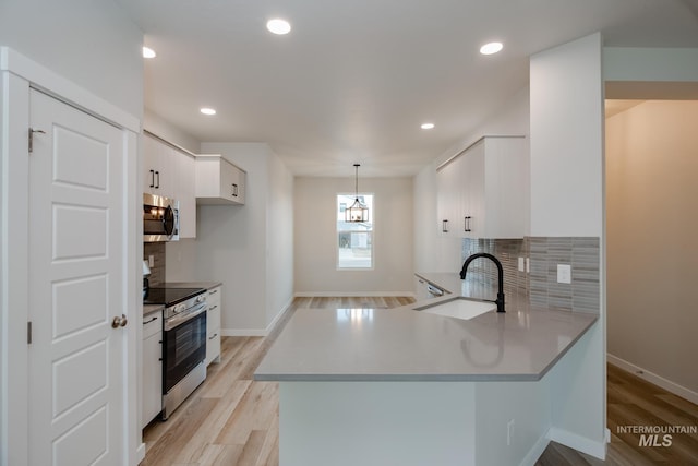 kitchen with appliances with stainless steel finishes, tasteful backsplash, sink, hanging light fixtures, and kitchen peninsula