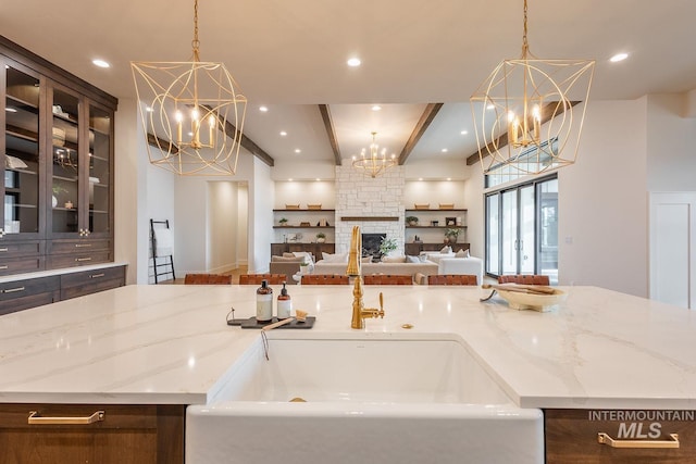 3426 N Hardwick Ave, Eagle, ID 83616 - kitchen featuring a chandelier, an island with sink, light stone counters, beamed ceiling, and open floor plan