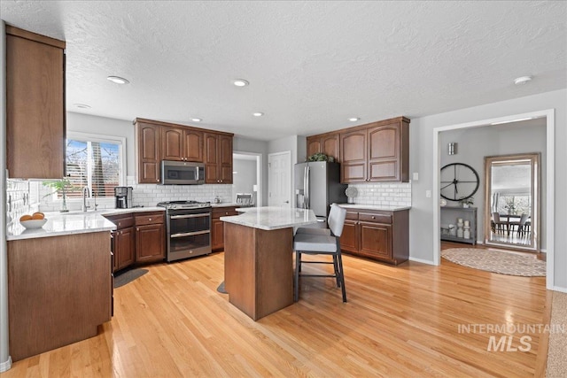 kitchen featuring a kitchen bar, light wood-style floors, appliances with stainless steel finishes, and a center island