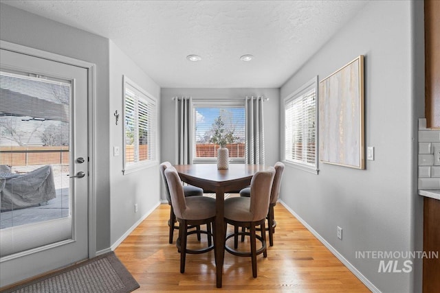 dining area with baseboards, light wood finished floors, and a textured ceiling