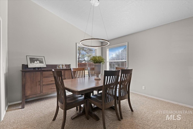 dining room featuring baseboards, light colored carpet, a textured ceiling, and lofted ceiling