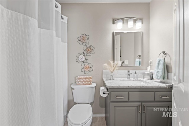 full bathroom featuring baseboards, toilet, and vanity