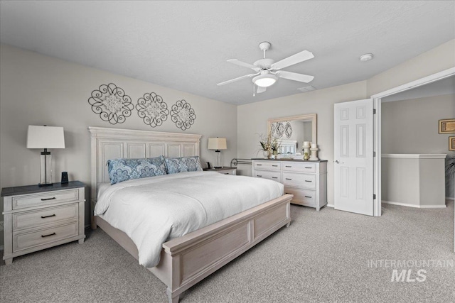 bedroom with a textured ceiling, a ceiling fan, baseboards, and light carpet