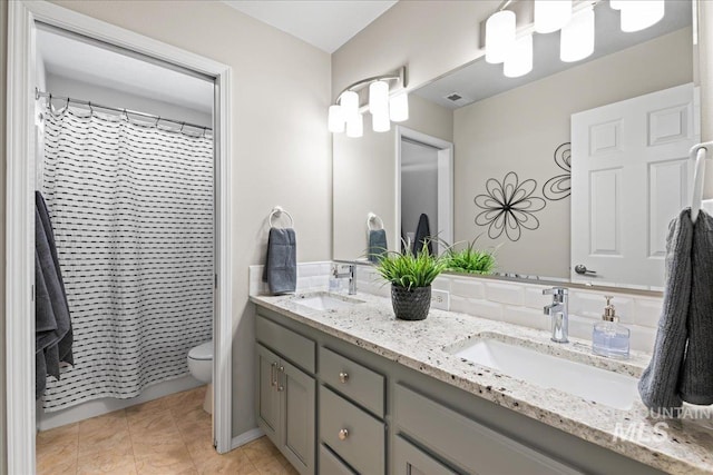 bathroom with a sink, visible vents, toilet, and double vanity