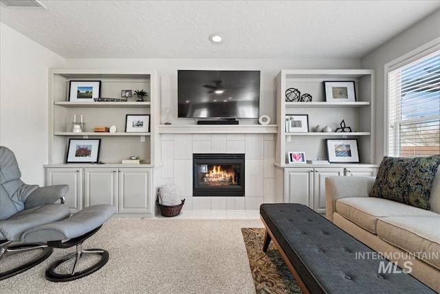 carpeted living room with a textured ceiling and a tile fireplace