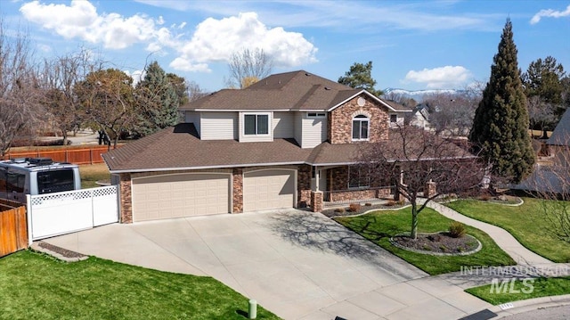 traditional-style home featuring a front yard, fence, driveway, roof with shingles, and stone siding