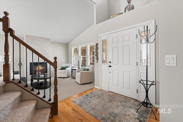 entryway featuring high vaulted ceiling, stairs, and wood finished floors