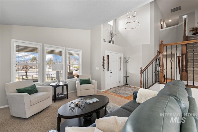 living area with visible vents, high vaulted ceiling, stairs, and baseboards