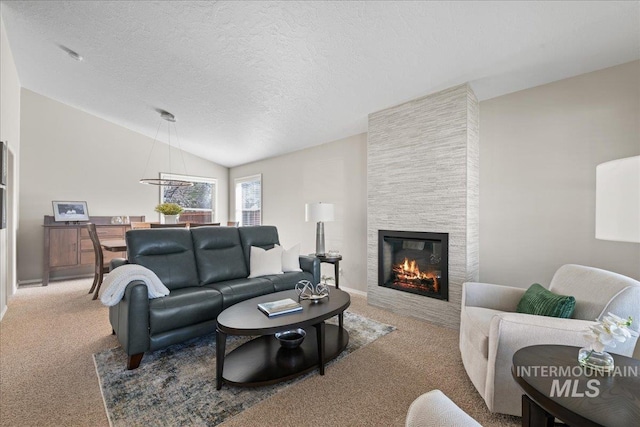 carpeted living area featuring a tiled fireplace, lofted ceiling, baseboards, and a textured ceiling