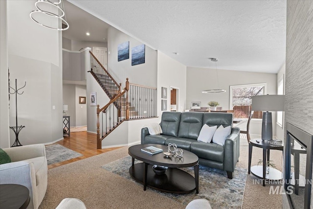 living area featuring baseboards, stairs, wood finished floors, a textured ceiling, and high vaulted ceiling