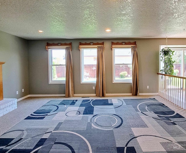interior space featuring a textured ceiling, baseboards, and multiple windows