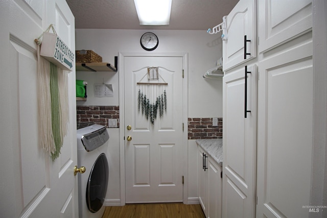 laundry area with washer / clothes dryer, cabinet space, and wood finished floors