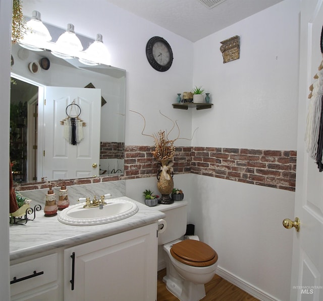 half bathroom featuring toilet, wood finished floors, and vanity