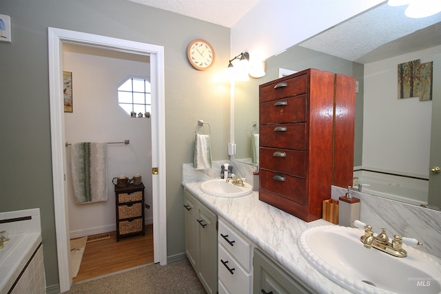 bathroom featuring a garden tub, double vanity, and a sink