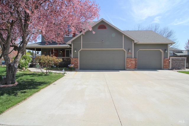 view of front facade with a porch, brick siding, a garage, a front lawn, and concrete driveway