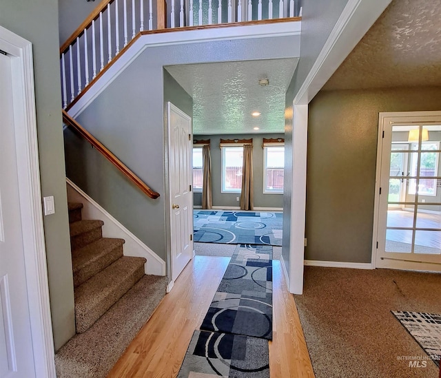 foyer featuring a textured ceiling, a healthy amount of sunlight, and stairs