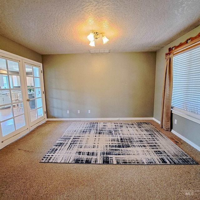 spare room with baseboards, visible vents, carpet floors, and a textured ceiling