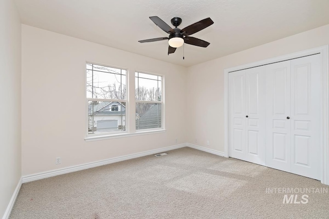 unfurnished bedroom with baseboards, visible vents, a ceiling fan, carpet floors, and a closet