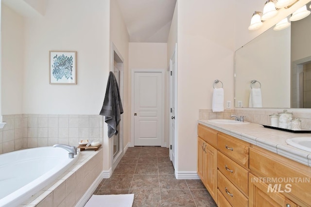 bathroom featuring a garden tub, a sink, tile patterned floors, double vanity, and a stall shower