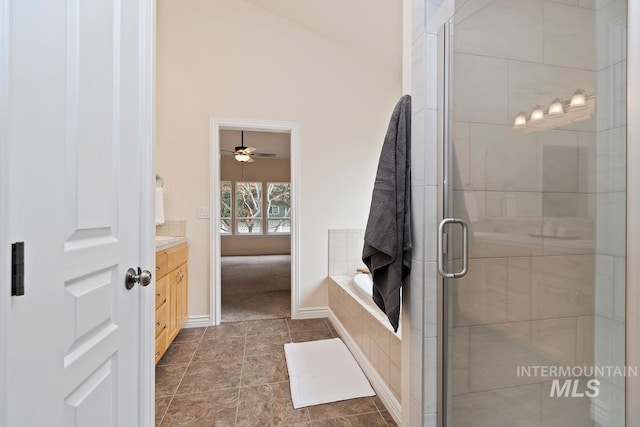 full bathroom with tiled bath, baseboards, vanity, and a shower stall