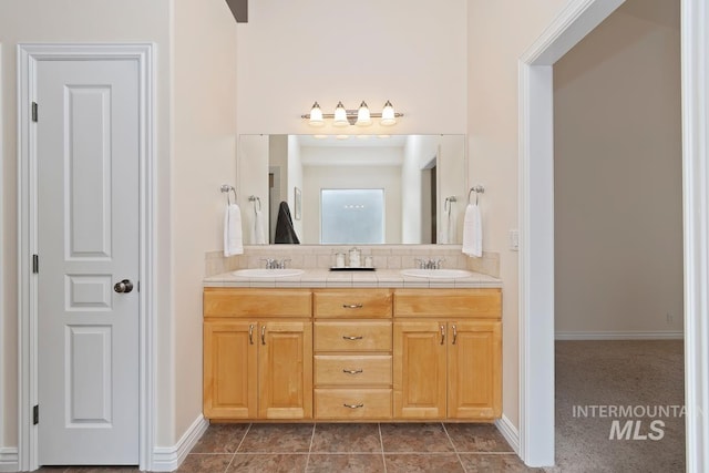 full bathroom featuring double vanity, baseboards, a sink, and tile patterned floors