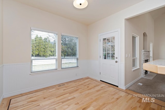 foyer entrance with a wainscoted wall, visible vents, and wood finished floors