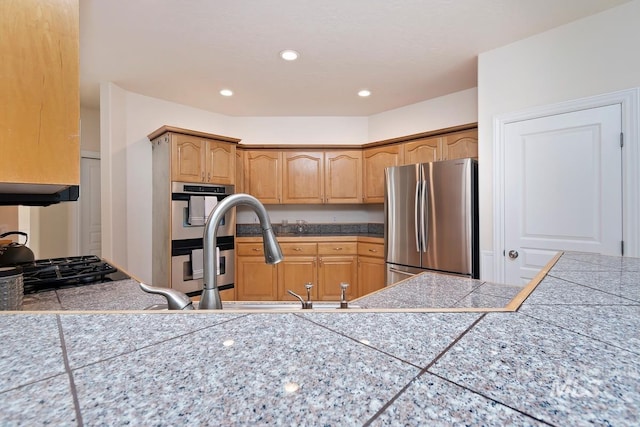 kitchen featuring tile countertops, stainless steel appliances, a sink, and recessed lighting