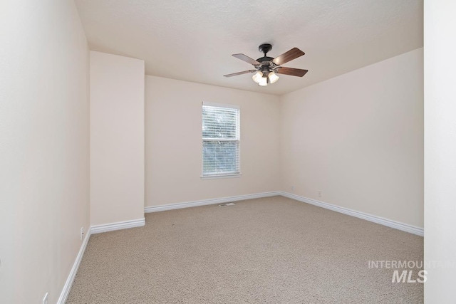 spare room featuring a textured ceiling, carpet floors, a ceiling fan, and baseboards