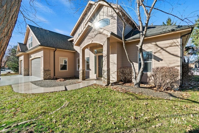 view of front facade with a garage, a front yard, concrete driveway, and stone siding