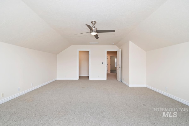 bonus room with baseboards, a ceiling fan, light colored carpet, vaulted ceiling, and a textured ceiling