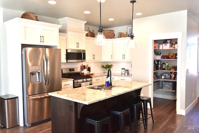 kitchen featuring a breakfast bar, a sink, appliances with stainless steel finishes, decorative backsplash, and dark wood-style floors