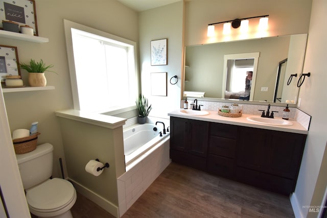 full bathroom featuring a garden tub, a sink, toilet, and wood finished floors