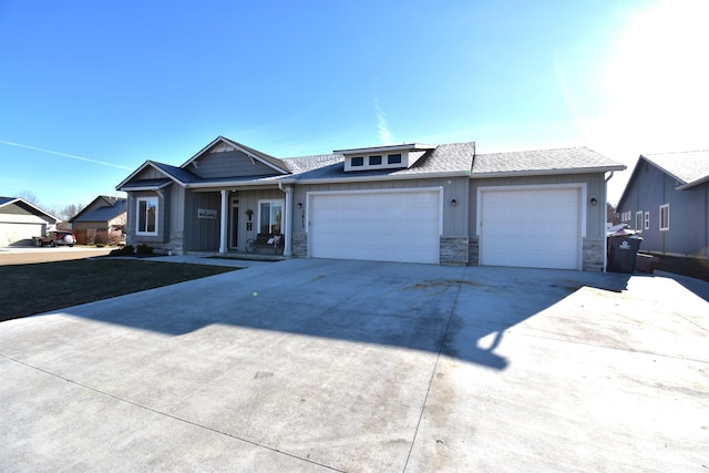 view of front facade with roof with shingles, board and batten siding, a garage, stone siding, and driveway