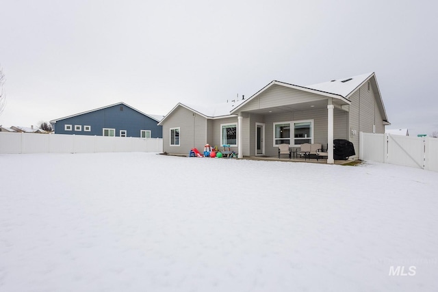 snow covered rear of property with a gate and fence