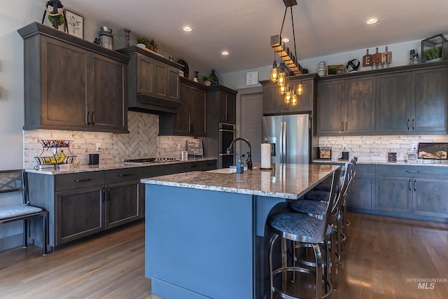 9473 W Suttle Lake Dr, Boise, ID 83714 - kitchen with stainless steel appliances, wood finished floors, dark brown cabinets, light stone countertops, and tasteful backsplash