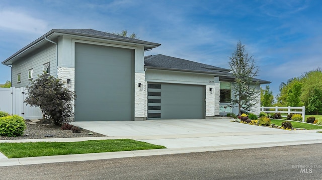 9473 W Suttle Lake Dr, Boise, ID 83714 - view of side of home with an attached garage, concrete driveway, stone siding, and a shingled roof