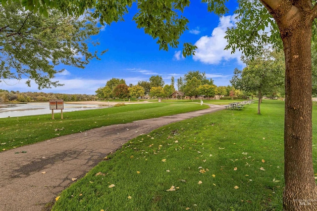 surrounding community with a water view and a lawn