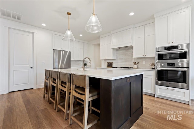 kitchen featuring white cabinets, appliances with stainless steel finishes, and pendant lighting