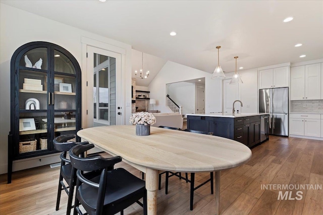 dining space featuring vaulted ceiling, light hardwood / wood-style flooring, and a chandelier