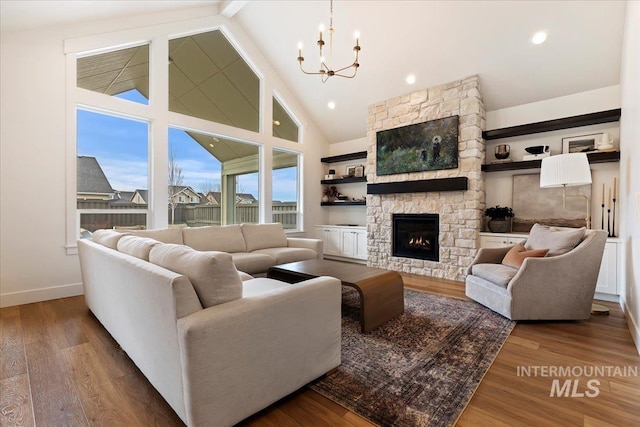 living room with a chandelier, high vaulted ceiling, a fireplace, and wood-type flooring