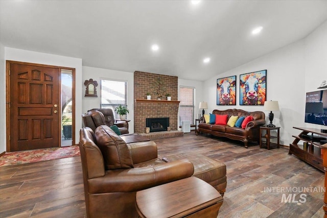 living room with vaulted ceiling, a fireplace, and hardwood / wood-style floors