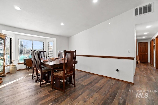 dining space featuring vaulted ceiling and dark wood-type flooring