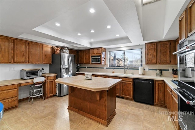 kitchen with a center island, stainless steel appliances, sink, backsplash, and a tray ceiling