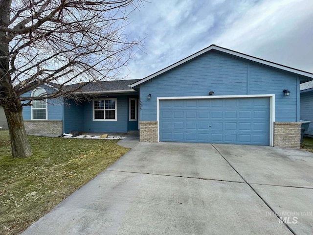 ranch-style home with an attached garage, brick siding, concrete driveway, and a front yard