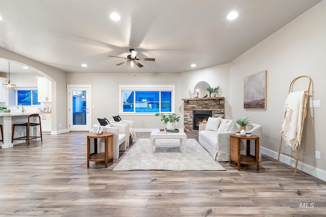 living area with recessed lighting, a fireplace, light wood-style floors, and a ceiling fan