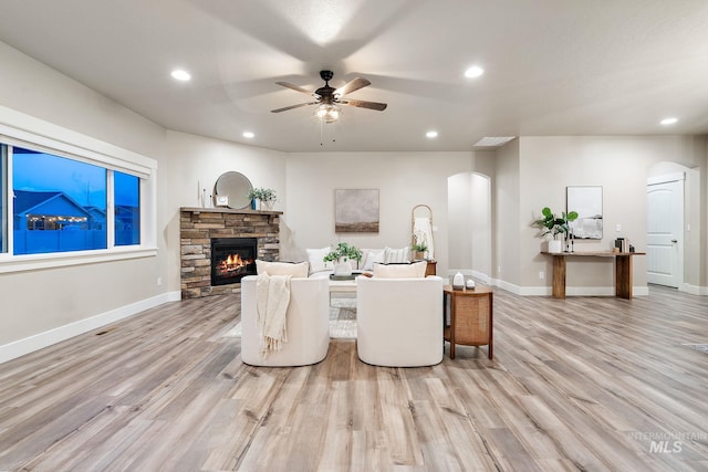 living room featuring arched walkways, light wood finished floors, and ceiling fan