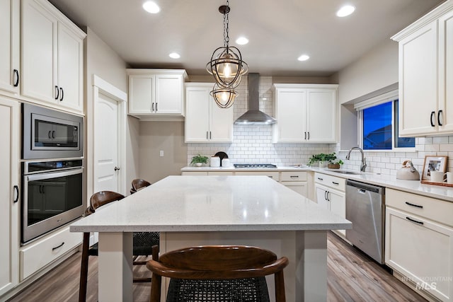 kitchen featuring a sink, a kitchen island, stainless steel appliances, a breakfast bar area, and wall chimney exhaust hood