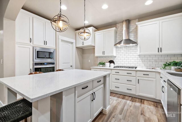 kitchen featuring recessed lighting, stainless steel appliances, light wood-style floors, wall chimney exhaust hood, and backsplash