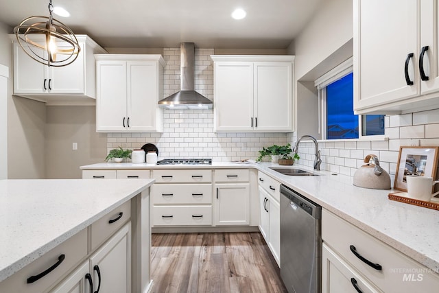 kitchen with white cabinets, stainless steel appliances, light wood-style floors, and wall chimney range hood