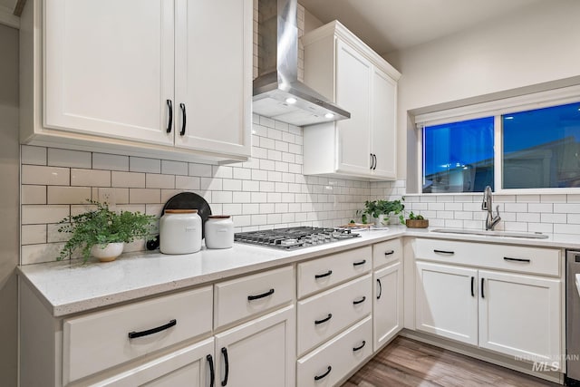 kitchen with tasteful backsplash, appliances with stainless steel finishes, wall chimney exhaust hood, and a sink